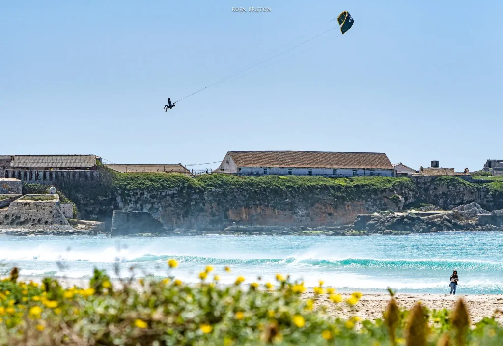 Kitesurfeur en l'air au-dessus d'une plage de sable blanc