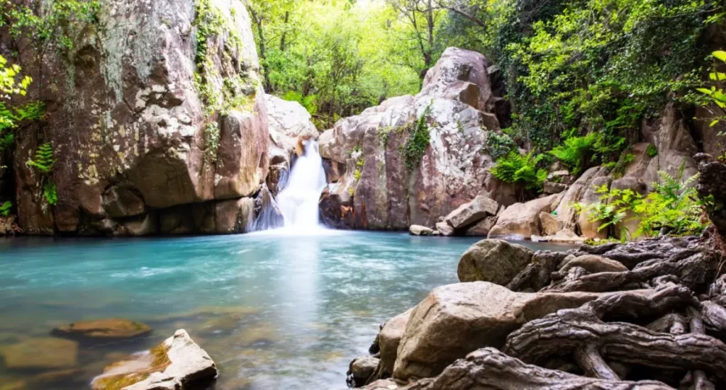Cascade tombant dans un bassin d'eau turquoise entre les rochers