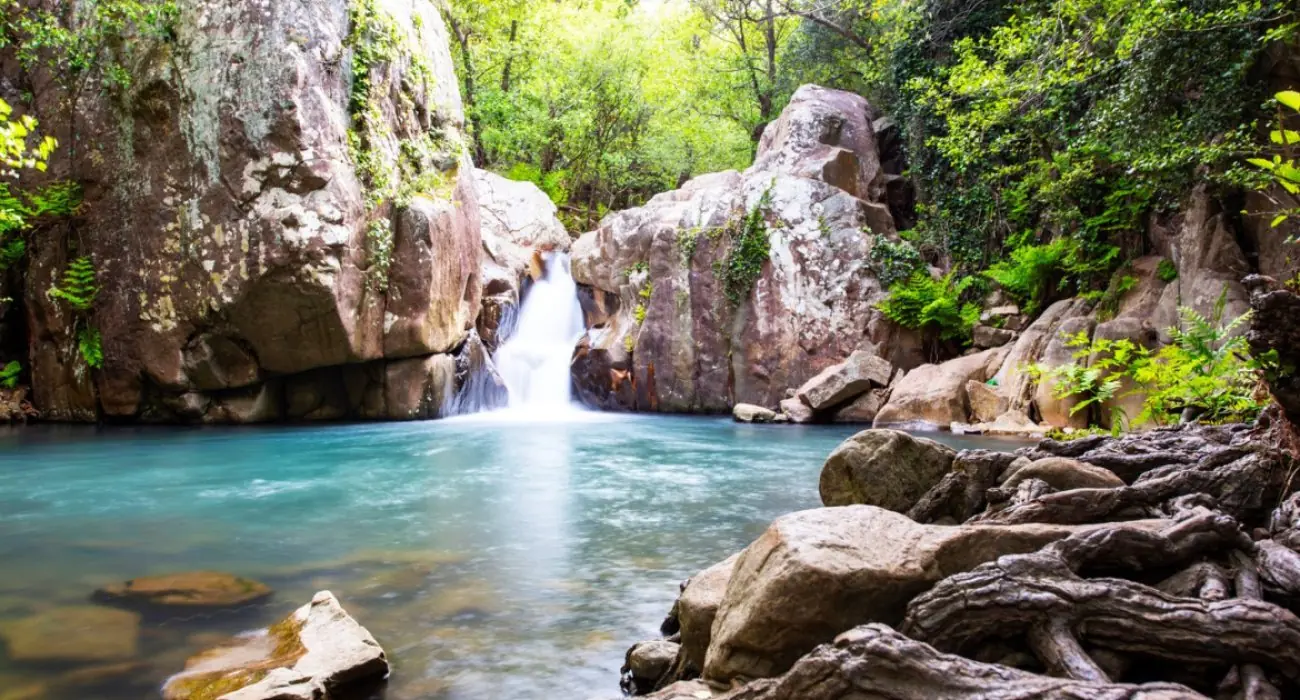 Cascade tombant dans un bassin d'eau turquoise entre les rochers