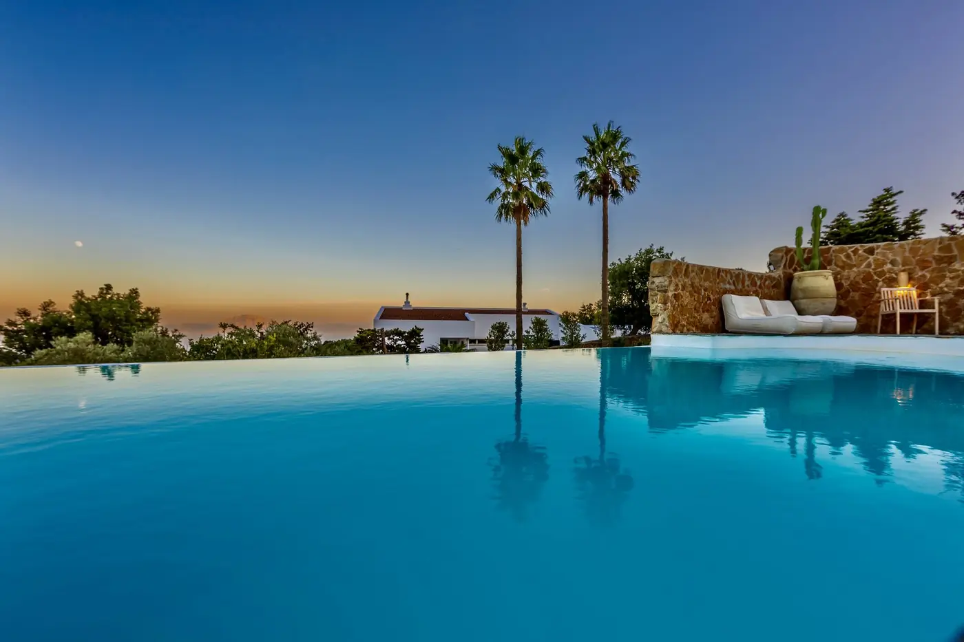 Piscine à débordement et palmiers sous un ciel bleu